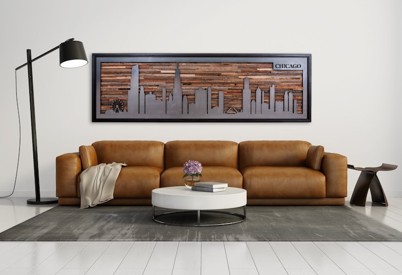 Peut inclure: Un canap&eacute; en cuir marron avec un plaid est plac&eacute; devant une &oelig;uvre d'art murale en bois et m&eacute;tal repr&eacute;sentant l'horizon de Chicago. L'&oelig;uvre d'art est encadr&eacute;e de noir et porte le mot "CHICAGO" dans le coin sup&eacute;rieur droit.