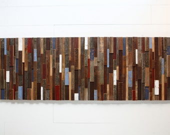 May include: A wall art piece made of reclaimed wood planks in various shades of brown, red, blue, and white. The planks are arranged in a random pattern to create a unique and rustic look.