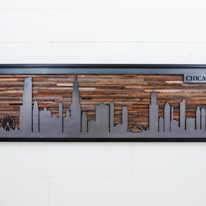 Peut inclure: Une d&eacute;coupe en m&eacute;tal de l'horizon de Chicago, avec le mot "CHICAGO" dans le coin sup&eacute;rieur droit, est mont&eacute;e sur un fond en bois. Le bois est compos&eacute; de planches de bois r&eacute;cup&eacute;r&eacute;es dans diff&eacute;rentes nuances de brun.