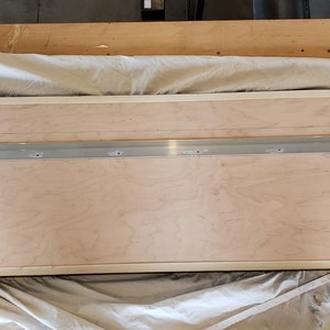 Peut inclure: L'arri&egrave;re d'un cadre rectangulaire en bois avec une bordure blanche. Une glissi&egrave;re m&eacute;tallique est fix&eacute;e au sommet du cadre &agrave; l'aide de vis. La glissi&egrave;re comporte plusieurs trous pour accrocher le cadre.