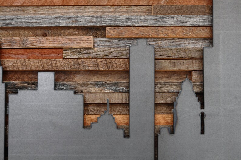 Peut inclure: Une silhouette de ville en m&eacute;tal mont&eacute;e sur un panneau de bois. La silhouette est en m&eacute;tal et peinte en argent. Le panneau de bois est en bois de r&eacute;cup&eacute;ration et pr&eacute;sente une vari&eacute;t&eacute; de couleurs et de textures.