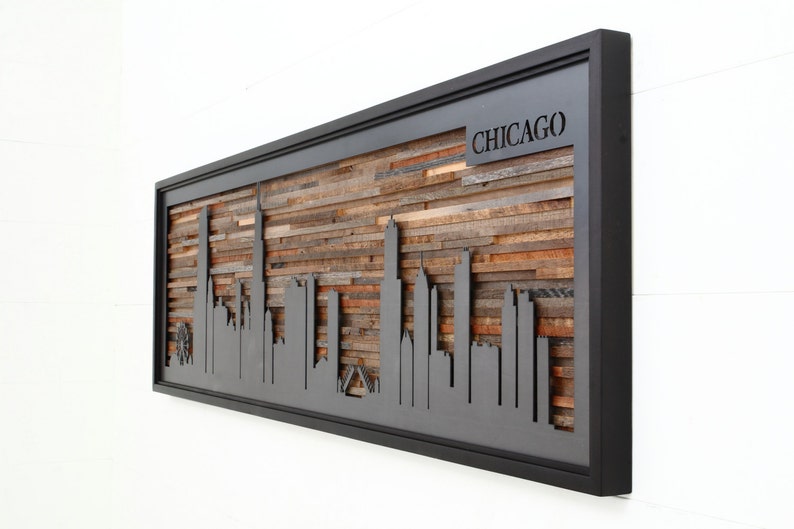 Peut inclure: Une &oelig;uvre d'art murale en bois encadr&eacute;e de noir repr&eacute;sentant une silhouette de l'horizon de Chicago. Le bois est dispos&eacute; en un motif horizontal et l'horizon est d&eacute;coup&eacute; dans le bois. Le cadre est noir et le bois est de diff&eacute;rentes nuances de brun. Le mot "CHICAGO" est d&eacute;coup&eacute; dans le bois en haut de la pi&egrave;ce.