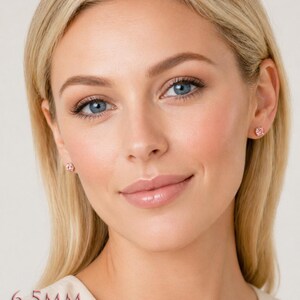 A woman wearing pair of four prong silver stud earrings set with 6.5mm round lab created padparadscha sapphires. Model image for size and styling reference — not a photo of the actual earrings.