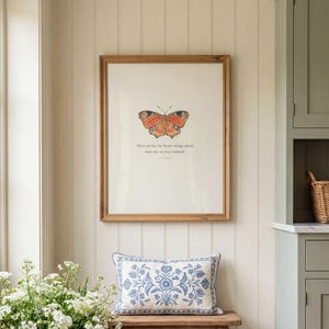 May include: A rectangular wooden framed wall art piece featuring a central orange and black butterfly illustration above the text, There are far, far better things ahead than any we leave behind, by C.S. Lewis, displayed above a wooden bench.