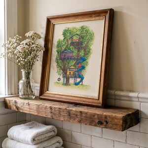 May include: A framed watercolor illustration of a multi-level treehouse nestled in a green tree, featuring a blue spiral slide, a yellow and purple structure, and a hanging tire swing, all enclosed in a rustic dark wood frame with gold trim.