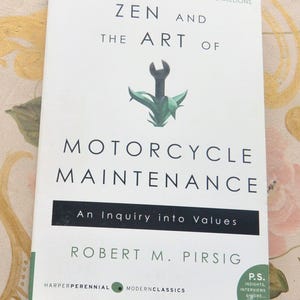 May include: A book titled "Zen and the Art of Motorcycle Maintenance" by Robert M. Pirsig. The cover features a wrench graphic with green accents. The book is a modern classic, published by HarperPerennial.