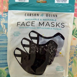 May include: A package of three Carson & Quinn washable and reusable face masks. The package includes masks in solid navy, navy flowers, and navy tie-dye patterns. The masks are adult size and made of a cotton polyester blend.