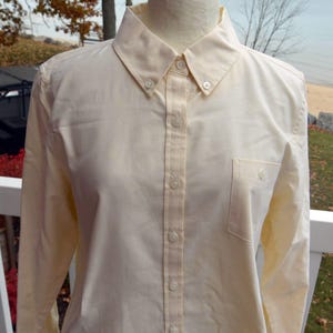 Op de afbeelding: Een lichtgeel overhemd met een button-down kraag en een borstzak. Het shirt met lange mouwen heeft knopen aan de voorkant en op de manchetten. Het shirt wordt op een mannequin getoond.