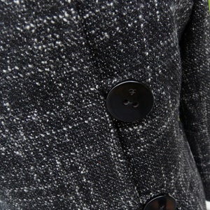 May include: Black and white tweed coat with a large black button. The button has a small raised design.