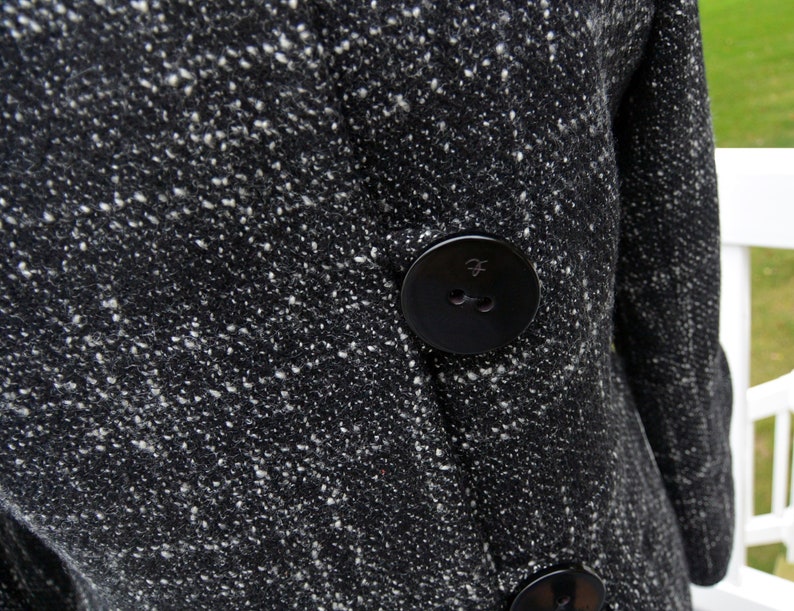 May include: Black and white tweed coat with a large black button. The button has a small raised design.