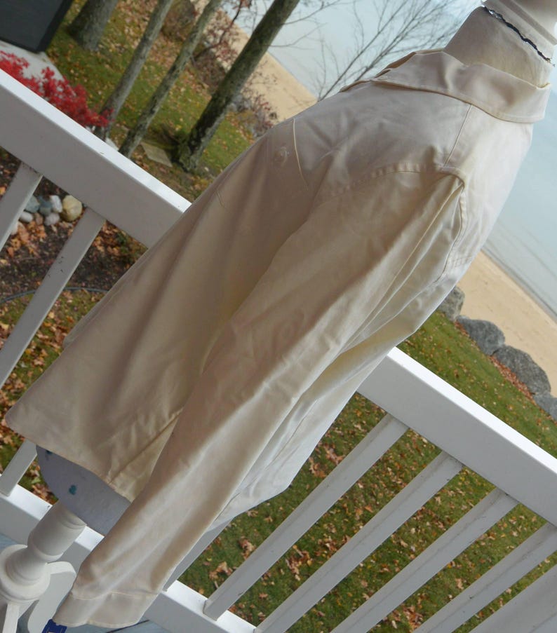 Puede incluir: Chaqueta beige claro con cuello y mangas largas. La chaqueta se exhibe en un maniqu&iacute;, mostrando su dise&ntilde;o y ajuste. La tela parece ser un material ligero, adecuado para climas de transici&oacute;n.