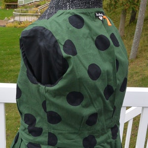 May include: A green and black polka dot vest with a black lining and a ruffled hem. The vest has a small black label with the text "Zadig & Voltaire" on the back.