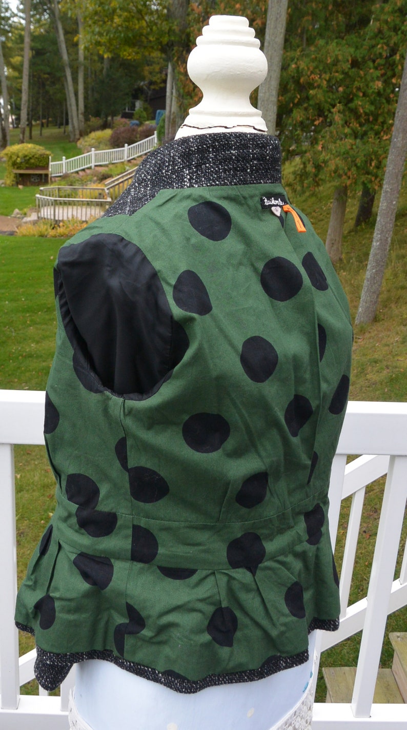 May include: A green and black polka dot vest with a black lining and a ruffled hem. The vest has a small black label with the text "Zadig & Voltaire" on the back.