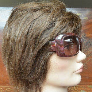 May include: A mannequin with brown hair wearing a pair of large, rectangular sunglasses with a brown and pink tortoiseshell frame.