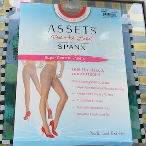 May include: A package of Assets Red Hot Label by Spanx shaping pantyhose. The package is light blue with text and images of pantyhose. Features include a super control panel, firm rear, and trim hips and thighs.