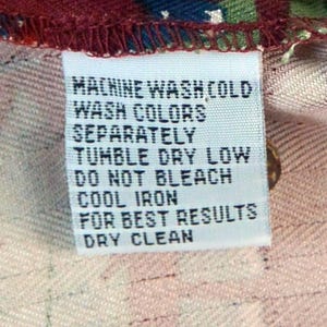 May include: A white fabric tag with black text, including washing instructions: Machine wash cold, wash colors separately, tumble dry low, do not bleach, cool iron, for best results, dry clean.