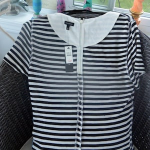 May include: A black and white striped dress with a white collar and a full-length zipper. The dress has short sleeves and a tag that reads "TALBOTS". The dress is hanging on a black hanger.