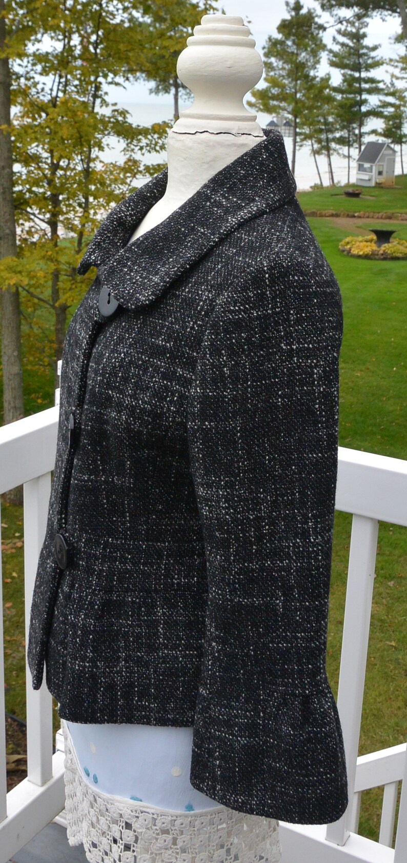 May include: A black and white tweed jacket with a button closure and a collar. The jacket has a slightly flared hem and is made of a soft, textured fabric.