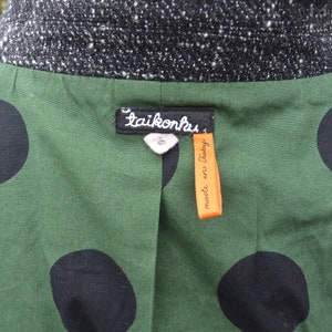 May include: A green and black polka dot jacket with a black tweed collar and a label that reads "taikonhus made in Italy."