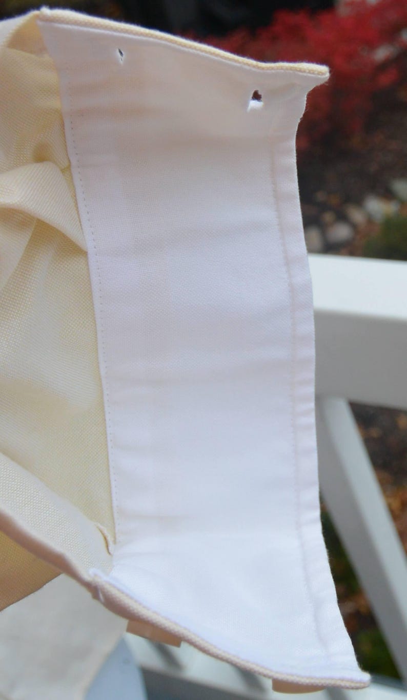 Puede incluir: Primer plano de un cuello de camisa blanco con un interior crema contrastante. El cuello tiene dos ojales y est&aacute; hecho de una tela suave y crujiente. Los bordes est&aacute;n cuidadosamente acabados con un sutil ribete de color claro. El fondo est&aacute; borroso.