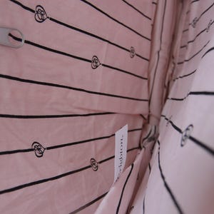 May include: Pink fabric bag interior with black striped pattern and heart motifs. A silver zip pull is visible. A white tag with the word "Brighton" is attached to the fabric.