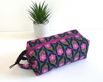 Neceser con cremallera y asa, de color magenta, con forma de caja y estampado floral, ideal para mujer.
