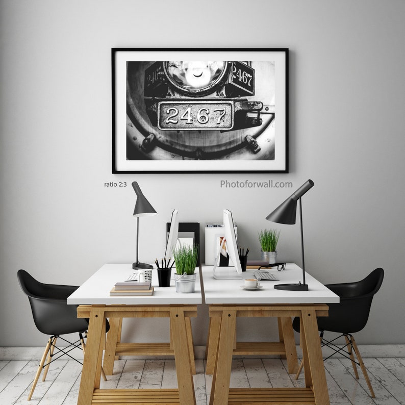 a white table with two black chairs and a picture on the wall