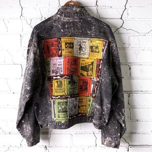 May include: A black acid-wash denim jacket featuring a large back panel composed of multiple colorful rectangular patches. Each patch displays various band names and concert graphics, including Bad Religion, Black Flag, and The Ramones.