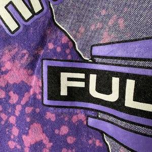 May include: Close-up of a purple t-shirt with a tie-dye effect. The word "FULL" is prominently displayed in white block letters within a black rectangle. The word "HAWAII" is partially visible at the top.