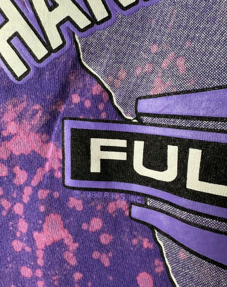 May include: Close-up of a purple t-shirt with a tie-dye effect. The word "FULL" is prominently displayed in white block letters within a black rectangle. The word "HAWAII" is partially visible at the top.