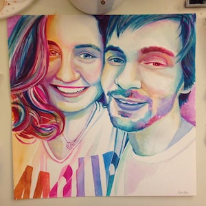 Pode incluir: Pintura em aquarela de um casal, uma mulher com cabelo longo rosa e um homem com cabelo azul, ambos sorrindo. A pintura &eacute; feita em um estilo vibrante com respingos de cor.