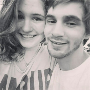 Pode incluir: Uma fotografia a preto e branco de um casal a sorrir para a c&acirc;mara. A mulher est&aacute; a usar uma camisa branca com um padr&atilde;o de riscas pretas e brancas. O homem est&aacute; a usar uma camisa branca.