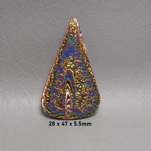 May include: A teardrop-shaped cabochon featuring a complex, multi-colored pattern of blue, green, yellow, red, and brown swirls. The surface has a glossy finish and measures 28 x 47 x 5.5mm. The design displays intricate, organic, layered textures.