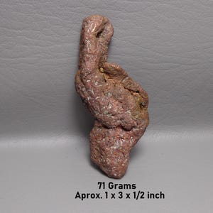 May include: A raw, reddish-brown copper nugget with a textured, uneven surface and metallic luster. The specimen weighs 71 grams and measures approximately 1 x 3 x 1/2 inches, as indicated by the text printed below the object.