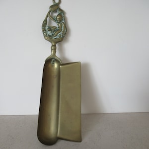 Può includere: Un set da camino in ottone con un manico decorativo che presenta un design a cherubino. Il manico ha l'iscrizione "Always True".