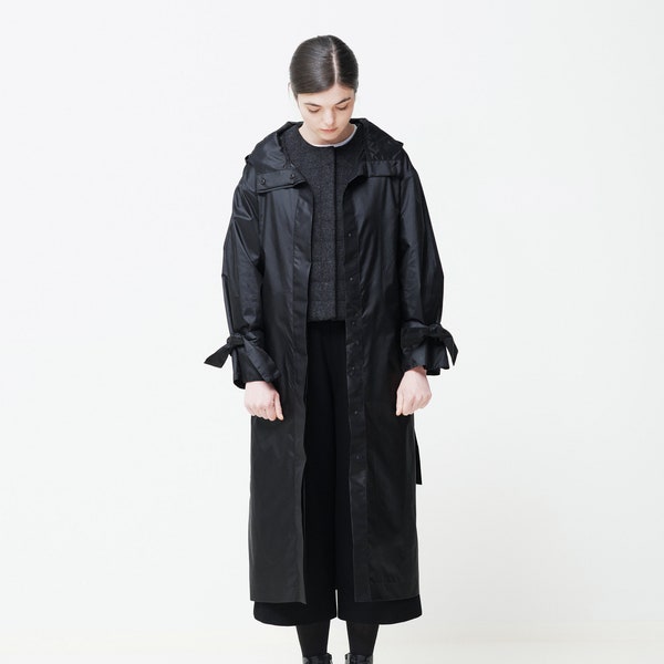 Imperméable à capuche avec ceinture et poches sur les coutures latérales, Trench-coat noir oversize imperméable, Veste de pluie longue urbaine minimaliste, Capsule de garde-robe