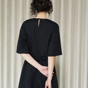May include: A black midi dress with a tie at the waist. The dress has a simple, elegant design and is perfect for a variety of occasions.