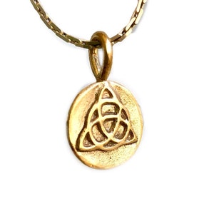 Könnte beinhalten: Eine goldene Kettenkette mit einem runden Anhänger mit einem keltischen Knotendesign.