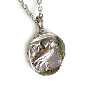 May include: Silver necklace with a round pendant featuring a detailed image of an owl. The pendant has a textured, antique-style finish.