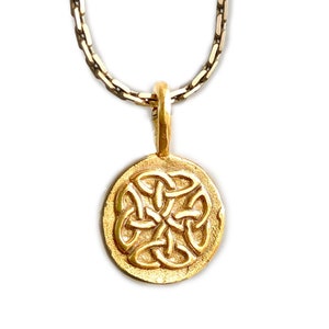 Könnte beinhalten: Eine goldene Kettenkette mit einem runden Anhänger mit einem keltischen Knotendesign.