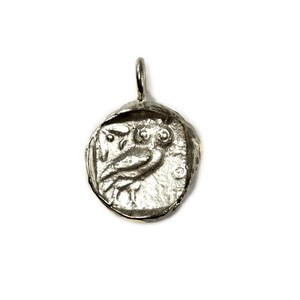 May include: Silver pendant featuring a detailed owl design. The pendant is round and has a textured surface.
