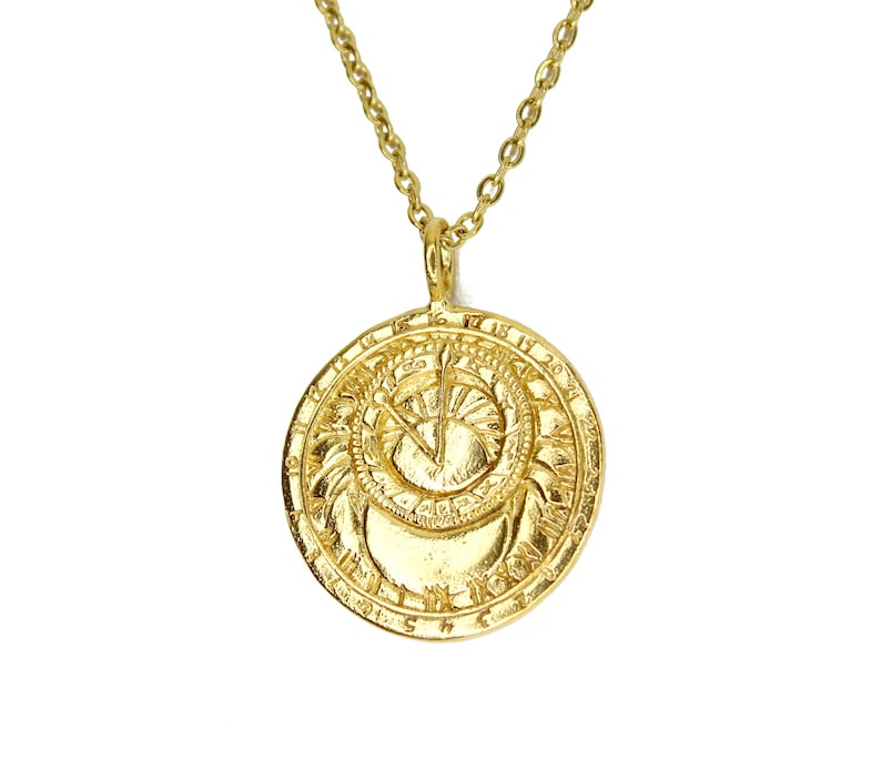 May include: Gold necklace with a round pendant featuring a sun and moon design with Roman numerals around the edge.