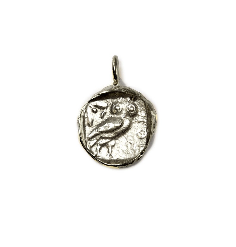 May include: Silver pendant featuring a detailed owl design. The pendant is round and has a textured surface.