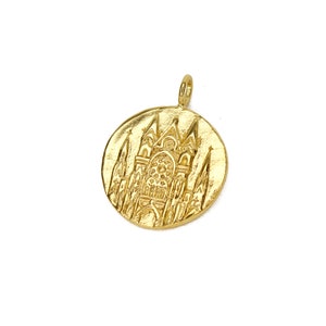 May include: Gold-toned pendant featuring a detailed embossed design of a cathedral building.