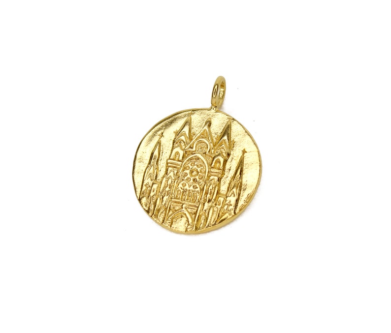 May include: Gold-toned pendant featuring a detailed embossed design of a cathedral building.
