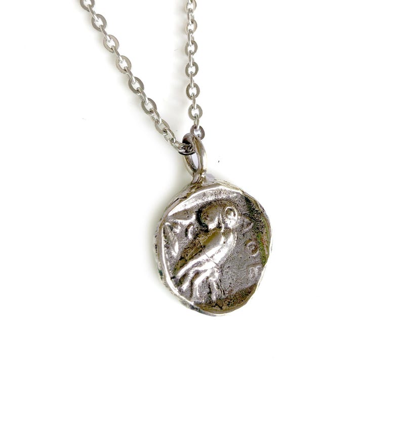May include: Silver necklace with a round pendant featuring a detailed image of an owl. The pendant has a textured, antique-style finish.