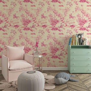 Op de afbeelding: Een kinderkamer met een roze fauteuil, een witte poef en een groene commode. De muren zijn bedekt met roze en cr&egrave;me behang met een herhalend patroon van paarden en bomen.