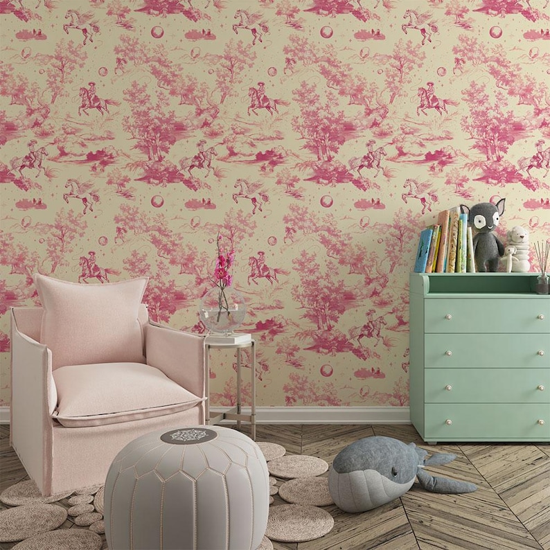 Op de afbeelding: Een kinderkamer met een roze fauteuil, een witte poef en een groene commode. De muren zijn bedekt met roze en cr&egrave;me behang met een herhalend patroon van paarden en bomen.
