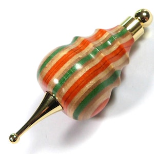 May include: A wooden bottle stopper with a gold top and a striped pattern of orange, green, and brown.