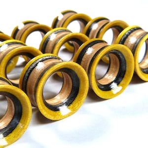 May include: A close-up of a row of yellow and black wooden ear gauges. The gauges have a striped pattern and are arranged in a line.